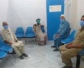 Four patients waiting on blue chairs at the medical centre