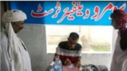 A man being registered at a desk under the trust's Urdu banner